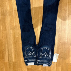 Miss Me midwaist bootcut jeans blå - Snygga blå jeans från Miss Me med bootcut och midwaist. Jeansen har markerade vita sömmar, coola bakfickor med broderade cool design !!!. Nypris 2400