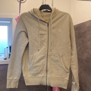 Polo Ralph lauren zip beige  - Snygg beige hoodie från Polo Ralph Lauren med dragkedja, huva och snörning. Klassisk broderad logga på bröstet och två fickor framtill. Den ser lite skrynklig ut på bilderna och de är för jag orka inte stryka den och den hängt i garderoben ett tag, annars är den i väldigt bra skick . Priset kan diskuteras vid snabb affär