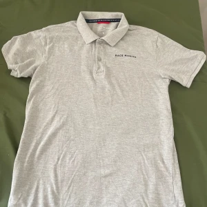 Ljusgrå pikétröja från Race Marine - Säljer en stilren ljusgrå pikétröja från Race Marine i storlek M. Tröjan har klassisk krage, korta ärmar och knäppning med tre knappar framtill. Perfekt för en clean och sportig look. Materialet är mjukt och skönt, troligtvis bomull.  Pris gör att diskutera 