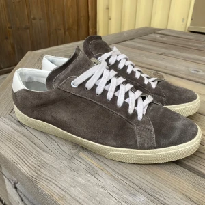 Saint Laurent Sl/06 - Säljer ett par bruna sneakers från Saint Laurent i storlek 42 1/2. Jätte bra skick på mockan och sulan. Enbart skor medföljer. Pris 1699 eller kom med bud! BVSA