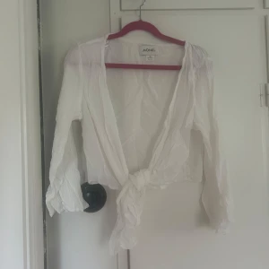 Vit knytblus  - Säljer en vit, tunn och luftig blus från Monki med långa ärmar och knyt framtill. Perfekt för varma dagar🥰 aldrig använd!