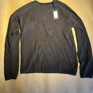 Mörkgrå tröja  - Snygg mörkgrå tröja i en stilren design. Tröjan har en texturerad yta och långa ärmar, perfekt för kyligare dagar. Passar bra till både jeans och chinos för en avslappnad look.