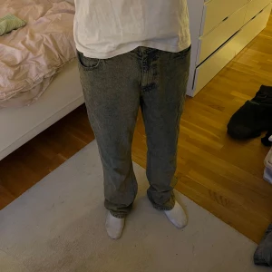 Smutsblåa jeans - Säljer ett par smutsblåa jeans med rak passform och klassisk femficksdesign. Byxorna har normal midja och stängs med dragkedja och knapp.