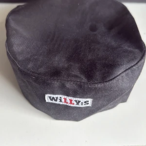 Willys mössa - Svart mössa med broderad Willys-logga framtill. Tillverkad i en blandning av polyester och bomull. Klassisk och enkel design som passar till många tillfällen.