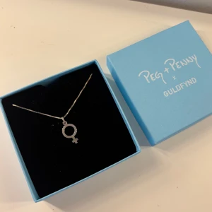 Silverhalsband, Peg + Penny x Guldfynd - Stilrent halsband i silver med kvinnosymbol som hänge. Kommer i original ask från Peg + Penny x Guldfynd. Perfekt accessoar för att lyfta din stil. Aldrig använt eller öppnat från ask.