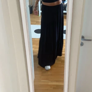 Svart långkjol med volang - Säljer en svart långkjol med volangdetaljer. Kjolen har en flowy och luftig passform som ger en avslappnad men ändå stilren look. Perfekt att matcha med crop tops eller enkla linnen.