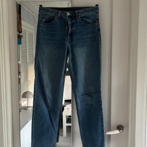 Blå raka jeans från Monki - Säljer ett par klassiska blå jeans från Monki med raka ben och normal passform. Jeansen stängs men knapp och dragkedja och är lite uppsydda. Perfekta till vardags och lätta att matcha.