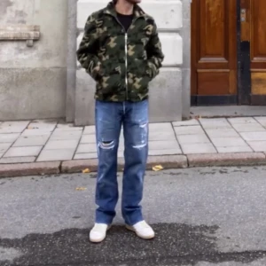 Vintage Levis Custom  - Säljer ett par blå jeans med raka ben och slitna detaljer på framsidan. Jeansen har klassisk femficksdesign och råa kanter vid bensluten. Perfekta för en avslappnad streetstil. Custom distressed, patches, stitching. Mått - Insida ben 78 cm Midja 40 cm 