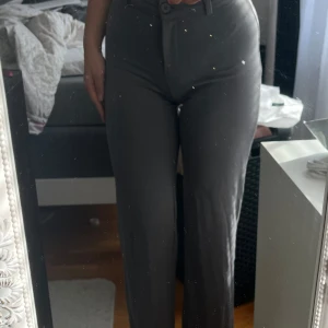 Gråa kostymbyxor med raka ben - Säljer ett par stilrena gråa kostymbyxor med normal passform och raka ben. Byxorna har hög midja, bälteshällor och stängs med knapp och dragkedja framtill. Perfekta för en clean och klassisk look.