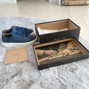 Blå mockasneakers från Sneaky Steve - Säljer ett par stilrena blå sneakers från Sneaky Steve i mocka med vita platta sulor och rund tå. Skorna har blå snörning och en klassisk, enkel design som passar till många outfits.