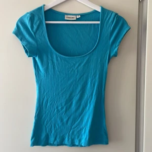 Turkos topp - En turkos ribbad topp, med vid urringning och väldigt kort ärm. 