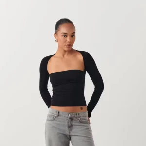 Svart långärmad tubtopp - Trendig svart tubtopp från Gina Tricot med långa ärmar och croppad passform. Toppen har en stilren, minimalistisk design och sitter tight mot kroppen. Perfekt för att skapa en snygg och modern look. Som ny 😍