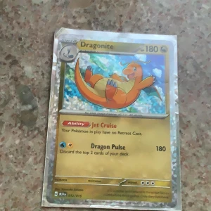 Pokémonkort Dragonite GX - Säljer ett Dragonite GX Pokémonkort med holografisk yta. Kortet har 180 HP och attacker som Jet Cruise och Dragon Pulse. Bakgrunden är blå med vita detaljer och motivet visar Dragonite i färgerna orange och gul.