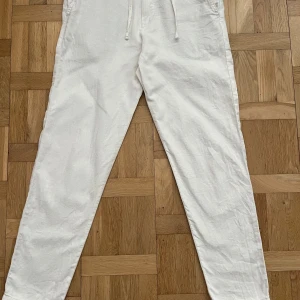 Vita linnebyxor från selected  - Säljer ett par vita linnebyxor med dragsko i midjan och raka ben. Byxorna har sidfickor fram och två bakfickor med knapp. Perfekta för varma dagar och en avslappnad stil. Köpta på jenasbolaget förra sommaren