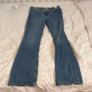 Blå bootcut jeans - Säljer ett par klassiska blå bootcut jeans med lätt slitning. Jeansen har fem fickor och normal passform upptill som går ut i ett vidare ben nertill. Perfekta för dig som gillar en retroinspirerad look.