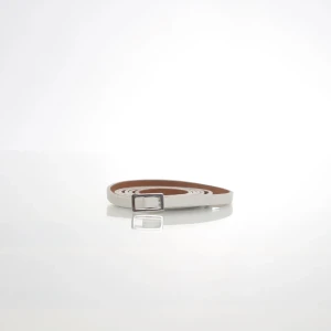 Vitt smalt bälte från Steps - Säljer ett smalt vitt bälte från Steps med silverfärgat spänne. Bältet är gjort i äkta skinn och har en stilren, minimalistisk design som passar till många olika outfits.
