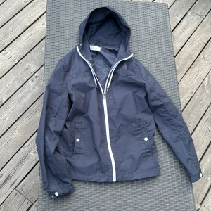 Peir One Jacka - Snygg marinblå peir one vindjacka med huva och vita dragsnören. Jackan har hel dragkedja framtill och två fickor med vita knappar. Perfekt för blåsiga dagar och enkel att matcha med det mesta. Har endast andvänt 3 gånger, skicka bara om du undrar något, jag skickar dagen du beställer eller dagen efter.