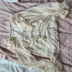 Beige blus volang  - Säljer denna söta blus med volanger fram och bak. Den är krämvit/beige och sitter skönt och luftigt, den har även ett extra lager inuti så den är inte genomskinlig 💕från vila storlek 38