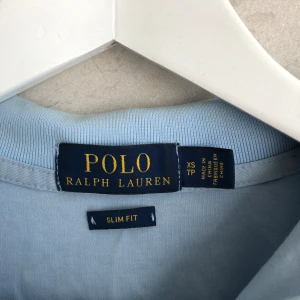Ljusblå pikétröja från Polo Ralph Lauren - Säljer en ljusblå pikétröja från Polo Ralph Lauren i slim fit-modell. Tröjan har korta ärmar, klassisk krage och broderad logga på bröstet. Perfekt för dig som gillar stilrena och klassiska plagg. Nypris 1700 kr 