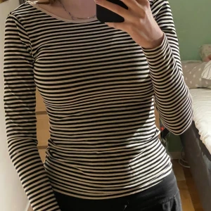 Randig långärmad topp med öppen rygg - Säljer en svartvit randig långärmad topp med tight passform och djup öppen rygg. Perfekt för dig som gillar stilrena basplagg med en twist. Tunn i materialet, passar till många olika outfits. Storleken är xs