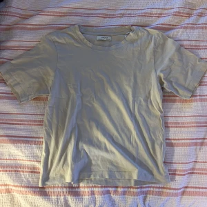 Beige basic t-shirt från Lindex XS - Enkel och stilren beige t-shirt från Lindex i storlek XS. T-shirten har rund halsringning och korta ärmar, perfekt för en clean och avslappnad look. Tillverkad i mjuk bomull som känns skön mot huden.
