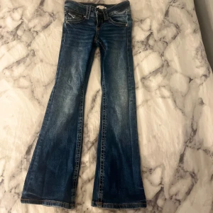 Blå bootcut jeans från Gina Tricot - Snygga blå bootcut jeans från Gina Tricot med klassisk femficksdesign och kontrastsömmar. Jeansen har medelhög midja och är tillverkade i stretchig denim för en bekväm passform. Perfekta för dig som gillar en retroinspirerad look.