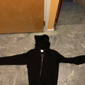 Svart hoodiejacka från Jack & Jones S - Svart hoodiejacka från Jack & Jones i storlek S. Jackan har dragkedja framtill, huva med snörning och är tillverkad i ekologisk bomull. Perfekt för en chill och avslappnad stil. Enkel och stilren design som funkar året runt.