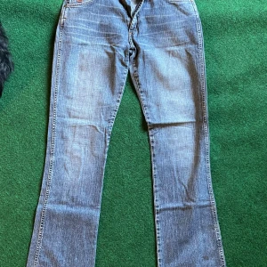 Blå bootcut jeans från Crocker - Snygga blå jeans från Crocker Bronson Original med klassisk bootcut-passform. Jeansen har en lätt tvättad look och raka ben som blir vidare nertill. Tillverkade i slitstarkt denimtyg, perfekta för en avslappnad stil.