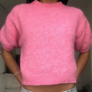 Rosa stickad tröja med kort ärm - Superfin rosa stickad tröja med korta puffärmar och ribbade muddar. Perfekt att styla med jeans eller kjol för en färgklick i garderoben.