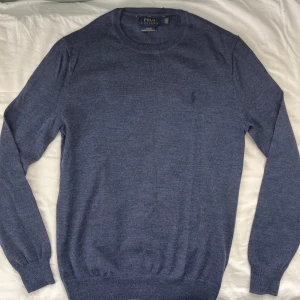 100% merinoull Ralph lauren tröja - Slim fit grå tröja från Polo Ralph Lauren i mjuk merinoull. Klassisk rund halsringning, diskret broderad logga på bröstet och långa ärmar. Perfekt för dig som gillar stilren och enkel design med premiumkänsla.