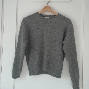 Grå och svart stickad tröja Uniqlo - Två stilrena stickade tröjor från Uniqlo i grått och mörk blå. Båda har rund halsringning, ribbade muddar och är långärmade. Perfekta för lager-på-lager och passar till allt. Den gråa är i bra skick, den blåa med men är knopprig utanpå. Man kan köpa båda för 160 eller den gråa för 100 och den blåa för 90.