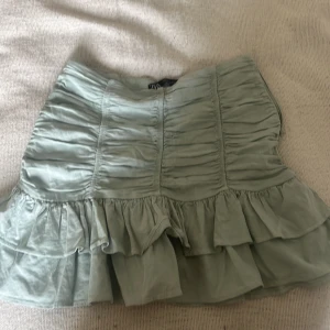 Ljusgrön volangkjol från Zara - Supersöt ljusgrön kortkjol från Zara med volanger och rynkade detaljer. Kjolen har en feminin och flowy känsla, perfekt för att skapa en trendig och lekfull look. Aldrig använt den 