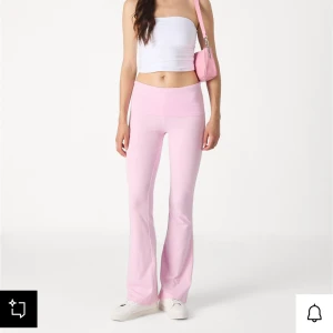 Soft touch folded trouser pink yogapants - Säljer ett par ljusrosa mjukisbyxor/yoga pants med bootcut-modell och hög midja. Byxorna är i mjukt material, perfekta för en chill och avslappnad stil. De har en bred linning och sitter snyggt över höfterna. Passar perfekt till sneakers och crop top.