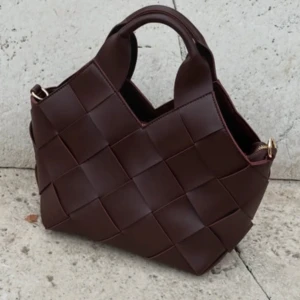 Brun flätad handväska i skinn - Säljer en snygg brun handväska med flätad design och korta handtag. 