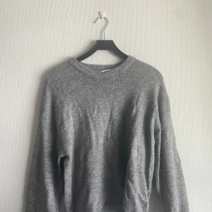 Grå stickad tröja  - En grå stickad tröja med rund halsringning och långa ärmar. Köpt på lager 157