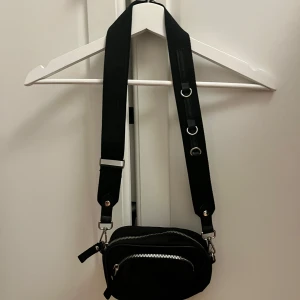 Svart axelväska från H&M🩷 -  svart axelväska med bred justerbar rem och silvriga dragkedjor. Perfekt storlek för mobilen, plånboken och andra småsaker🩷