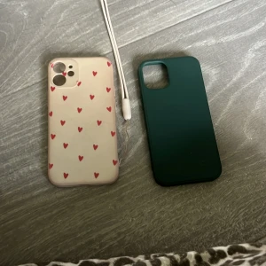 Två mobilskal, hjärtan & grön - Säljer två mobilskal till iPhone. Ett är ljusbeige med små röda hjärtan och har en vit handledsrem, det andra är helgrönt och stilrent. Båda är mjuka och flexibla, perfekta för att skydda mobilen och ge den en personlig touch.