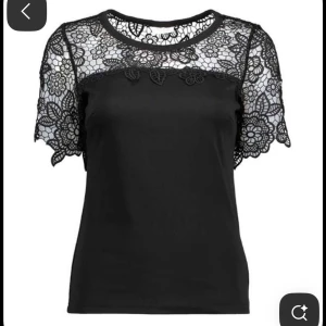 Svart blus med spetsdetaljer - Supersnygg svart blus med korta ärmar och vacker spets upptill och över axlarna.