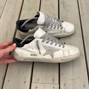 Golden Goose Superstar Vit - Golden Goose superstar i storlek 44 men skulle mycket väl kunna passa 43. De är använda ett fåtal gånger och har mindre defekter på sulorna därav priset. Svåra att få tag på samt att dem har ett nypris på upp mot 6 tusen gör att detta blir en svårslagen deal trots slitaget! Orginalbox samt dustbag följer med. Skriv för frågor, pris kan diskuteras.