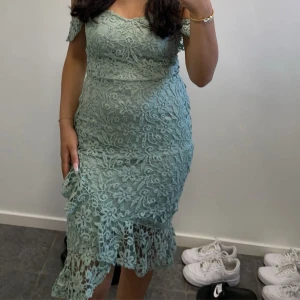 Mintgrön spetsklänning offshoulder - Superfin mintgrön klänning med offshoulder och blommig spets. Figurnära passform med volangdetalj nertill. Perfekt för dig som gillar romantisk stil och vill sticka ut med en unik färg. Klänningen går ungefär ner till knäna på mig som är 160 cm. Den har tidigare gått sönder lite på insidan så jag har sytt (se bild 3) och på samma ställe har den lossnat lite på andra armen (se bild 4) men det är absolut inget som syns på utsidan när man väl har på sig klänningen. 