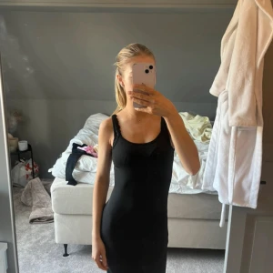 Svart långklänning med slits - Säljer en svart långklänning med smala axelband och tight passform. Klänningen har en snygg slits på sidan. Perfekt för dig som gillar stilrena och enkla plagg. Materialet känns mjukt och stretchigt.