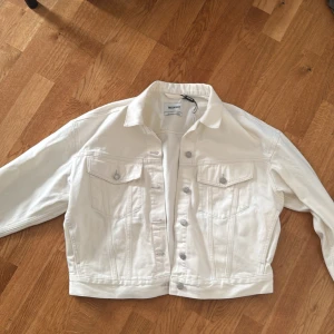 Vit jeansjacka från Weekday, stl M - Vit jeansjacka från Weekday. Klassisk modell med knappar framtill, två bröstfickor och raka sömmar. Jackan har en croppad passform och långa ärmar. Aldrig använd. Pris kan diskuteras! 