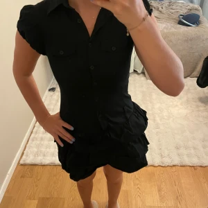 Svart kläning  - Svart kort kläning. Materialet är lite likt jeans och har en snygg skjort liknande överdel💘