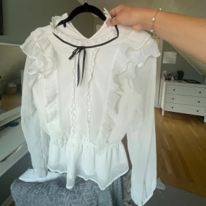 Blus - Vit långärmad blus men volang  från lindex, har även en svart roset där fram, passar till de mesta