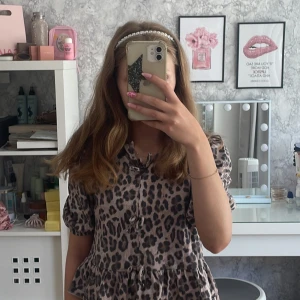 Leopardmönstrad blus med volang - Supersöt blus med leopardmönster i beige och svart/grått. Modellen har puffiga korta ärmar, volang nertill och knytning framtill mitten och lengdsner. Perfekt för dig som vill sticka ut lite extra med ett djurmönster och en feminin touch. Jag klippte lappen för att den var oskön så att du vet❤️