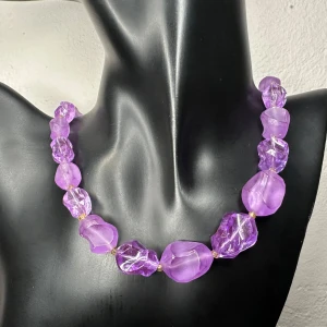 Chunky lila retrohalsband Vintage 60-tal 70-tal Fint skick - Retro halsband från 1960–1970-talet, inropat på auktion med äldre bijouterier. Halsbandet består av stora, oregelbundet formade lila akrylpärlor, avdelade med små guldtonade mellanpärlor. Längden är ca 47 cm och de största pärlorna mäter upp till ca 1,5 cm. Enkel fjäderlås i metall.  Jag prutar inte men erbjuder rabatt vid köp av flera saker. Jag rensar både smyckesskrin och garderob, så passa på att kika på mina andra annonser! 