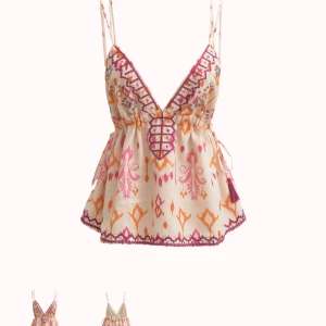 Mönstrad linnetopp med snörning - Superfin linnetopp med smala axelband och färgglatt mönster i rosa och orange på beige botten. Toppen har v-ringning, snörningsdetalj framtill och volangkant nertill. Perfekt för sommaren! Helt ny, säljer för den var för stor.