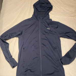 Blå tränings jacka från Lacoste Sport - Snygg marinblå tränings jacka från Lacoste Sport med huva och dragkedja hela vägen. Jackan är knappt använd och vid funderingar om passform eller mer bilder tveka inte på att skriva😉