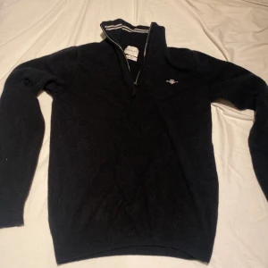 Svart halvziptröja i lammull från Gant - Svart långärmad tröja från Gant i superfin lammull. Tröjan är i storlek M men tvättades fel efter första användning sitter numera som en XS/S. Tröjan är använd 1 gång och är i perfekt skick. vid funderingar tveka inte på att skriva😁
