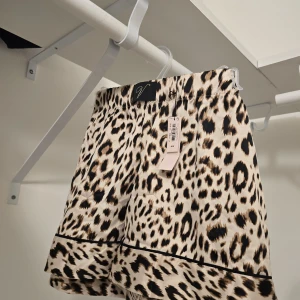 Leopardmönstrade shorts i satin - Snygga shorts från Victoria's secret med leopardmönster i beige, svart och brunt. De har en loose passform, elastisk midja och en glansig satinfinish. Perfekta för dig som vill sticka ut med en trendig look.